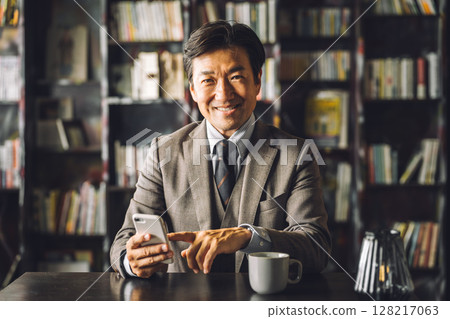 Asian male businessman using smartphone in library, study (e-book, reading, literature, education, app) 128217063