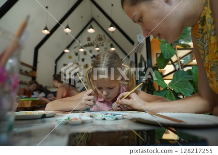 A young mother and her daughter enjoy a creative art session at home  128217255