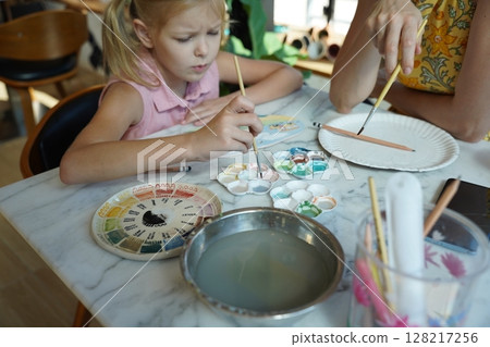 A young mother and her daughter enjoy a creative art session at home  128217256