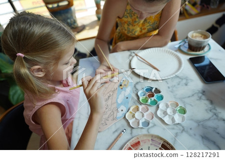 A young mother and her daughter enjoy a creative art session at home  128217291
