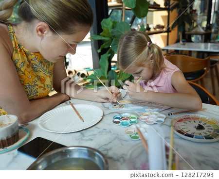 A young mother and her daughter enjoy a creative art session at home  128217293