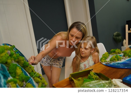 A mother and her daughter craft vibrant natural landscapes  128217354
