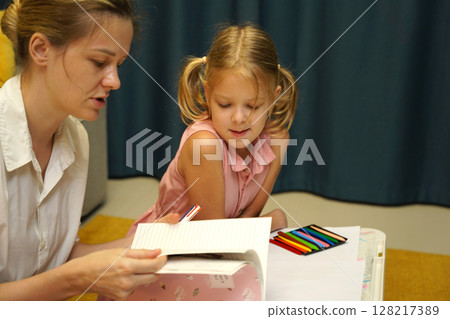 A mother supports her daughter with homework A mother supports her daughter with homework 128217389