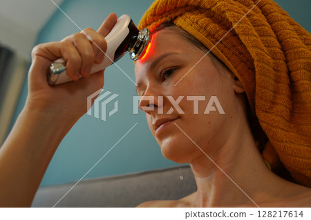 Young woman using infrared massager  128217614