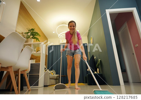 A woman is cleaning her living room at home A woman is cleaning her living room at home 128217685