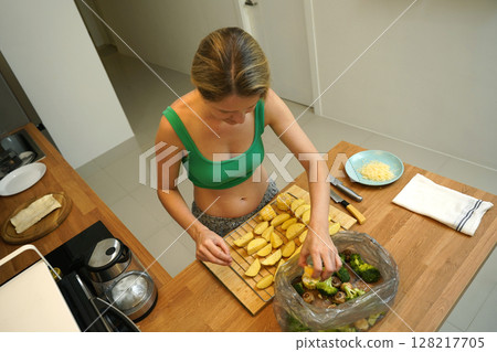 A young woman joyfully prepares a variety of healthy meals  128217705