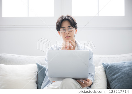 A man thinking while looking at a computer. He is troubled and worried. 128217714