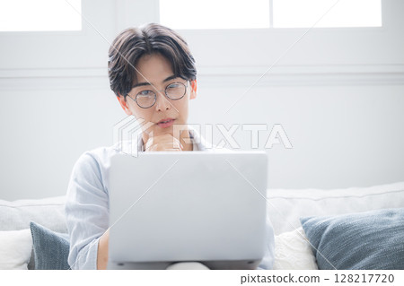 一名男子一邊看著電腦一邊思考。他感到煩惱和憂慮。 128217720