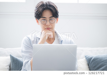一名男子一邊看著電腦一邊思考。他感到煩惱和憂慮。 128217721
