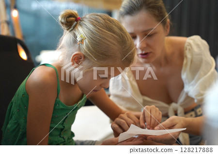 Mother and her daughter paint Halloween cookies  128217888