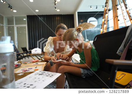 Mother and her daughter paint Halloween cookies Mother and her daughter paint Halloween cookies 128217889