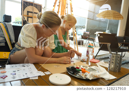 Mother and her daughter paint Halloween cookies  128217910