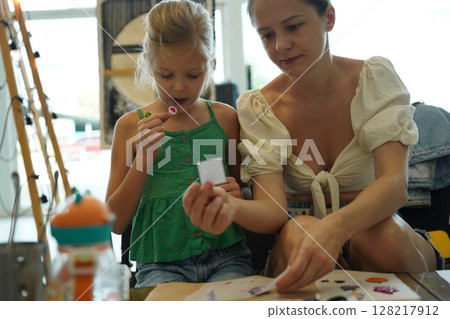 Mother and her daughter paint Halloween cookies  128217912