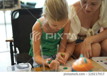 Mother and her daughter paint Halloween cookies Mother and her daughter paint Halloween cookies 128217917
