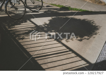 The shadow of a garden tree and a telephone pole falls on the parking space in the garden of a house 128217927