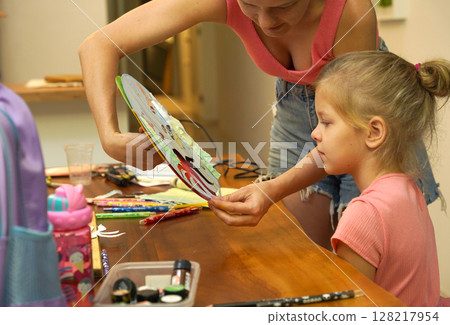 A mother and her young daughter engage in a colorful painting activity  128217954