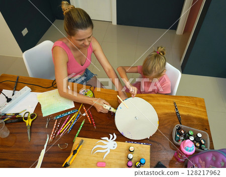 A mother and her young daughter engage in a colorful painting activity  128217962
