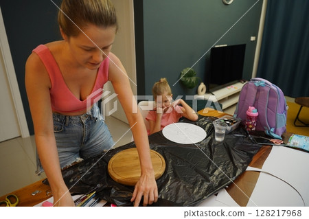 A mother and her young daughter engage in a colorful painting activity  128217968
