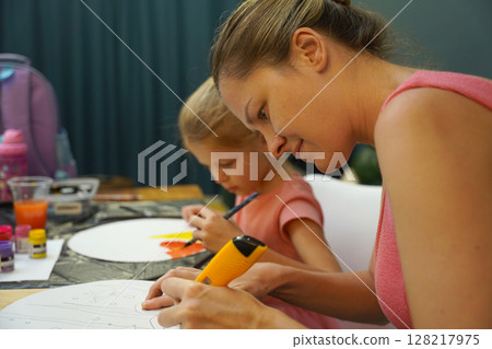 A mother and her young daughter engage in a colorful painting activity  128217975