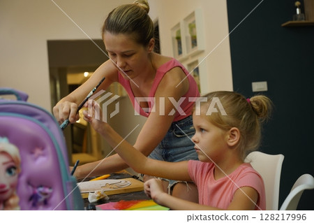 A mother and her young daughter engage in a colorful painting activity A mother and her young daughter engage in a colorful painting activity 128217996