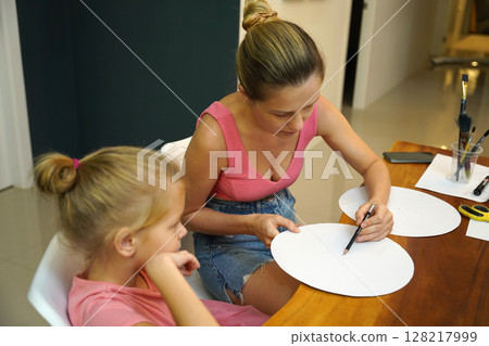 A mother and her young daughter engage in a colorful painting activity  128217999
