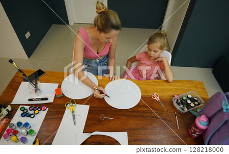 A mother and her young daughter engage in a colorful painting activity  128218000