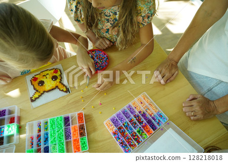 Teacher in workshop teched two girls how to assemble a thermo mosaic Teacher in workshop teched two girls how to assemble a thermo mosaic 128218018