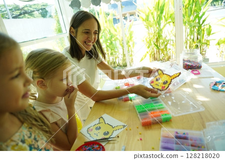Teacher in workshop teched two girls how to assemble a thermo mosaic Teacher in workshop teched two girls how to assemble a thermo mosaic 128218020