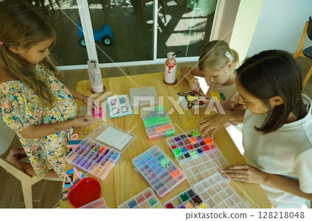 Teacher in workshop teched two girls how to assemble a thermo mosaic Teacher in workshop teched two girls how to assemble a thermo mosaic 128218048