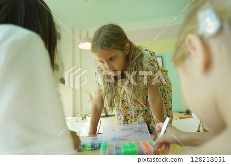 Teacher in workshop teched two girls how to assemble a thermo mosaic  128218051