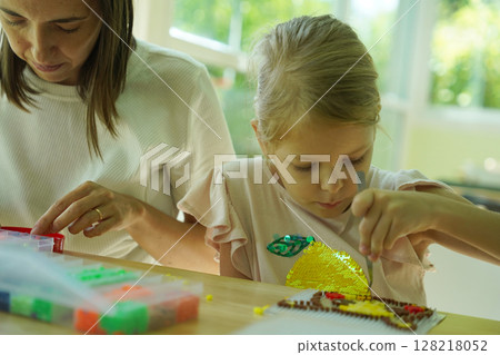 Teacher in workshop teched two girls how to assemble a thermo mosaic  128218052