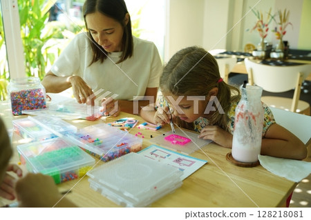 Teacher in workshop teched two girls how to assemble a thermo mosaic  128218081