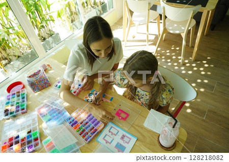 Teacher in workshop teched two girls how to assemble a thermo mosaic Teacher in workshop teched two girls how to assemble a thermo mosaic 128218082