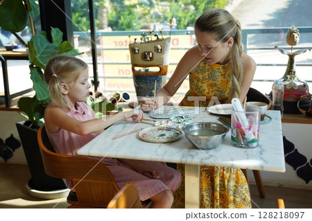 A young mother and her daughter enjoy a creative art session at home  128218097