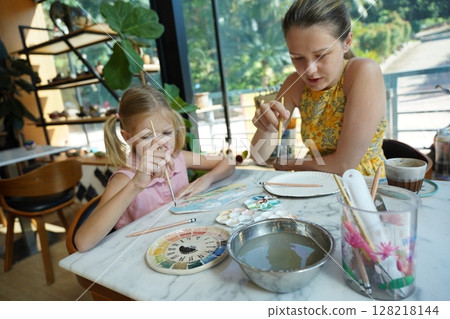 A young mother and her daughter enjoy a creative art session at home  128218144