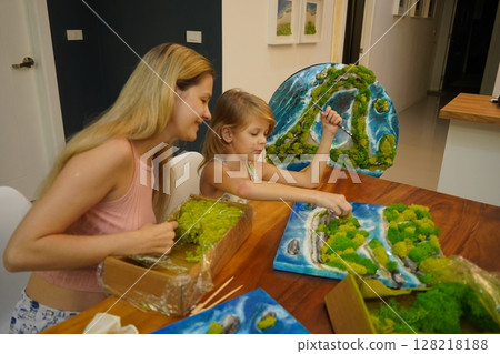 A mother and her daughter craft vibrant natural landscapes  128218188