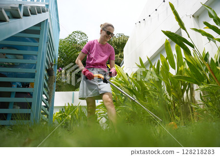 A young woman trims her beautiful garden A young woman trims her beautiful garden 128218283