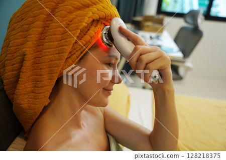 Young woman using infrared massager  128218375