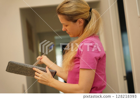 A woman is cleaning her living room at home A woman is cleaning her living room at home 128218393