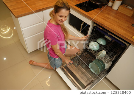 Young woman takes dishes out of the dishwasher machine 128218400