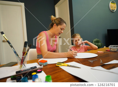 A mother and her young daughter engage in a colorful painting activity  128218701