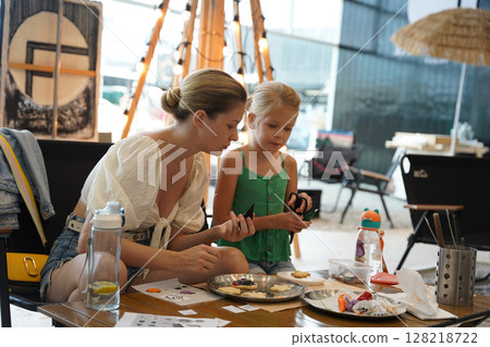 Mother and her daughter paint Halloween cookies  128218722