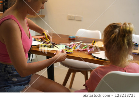 A mother and her young daughter engage in a colorful painting activity  128218725