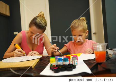 A mother and her young daughter engage in a colorful painting activity  128218735