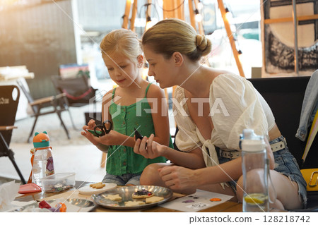 Mother and her daughter paint Halloween cookies Mother and her daughter paint Halloween cookies 128218742