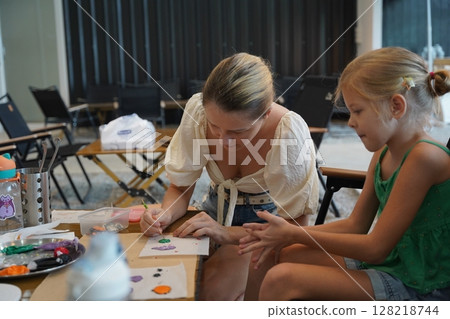 Mother and her daughter paint Halloween cookies Mother and her daughter paint Halloween cookies 128218744
