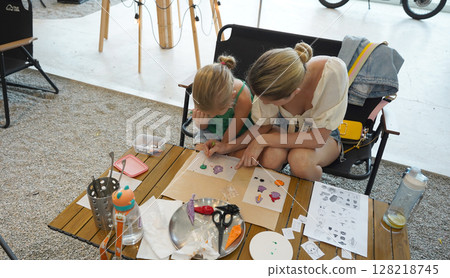 Mother and her daughter paint Halloween cookies  128218745
