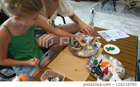 Mother and her daughter paint Halloween cookies Mother and her daughter paint Halloween cookies 128218760