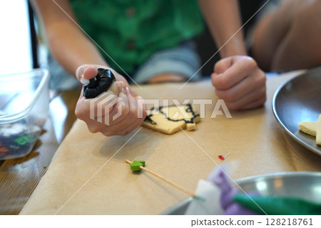 Mother and her daughter paint Halloween cookies  128218761