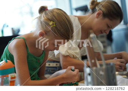 Mother and her daughter paint Halloween cookies  128218762